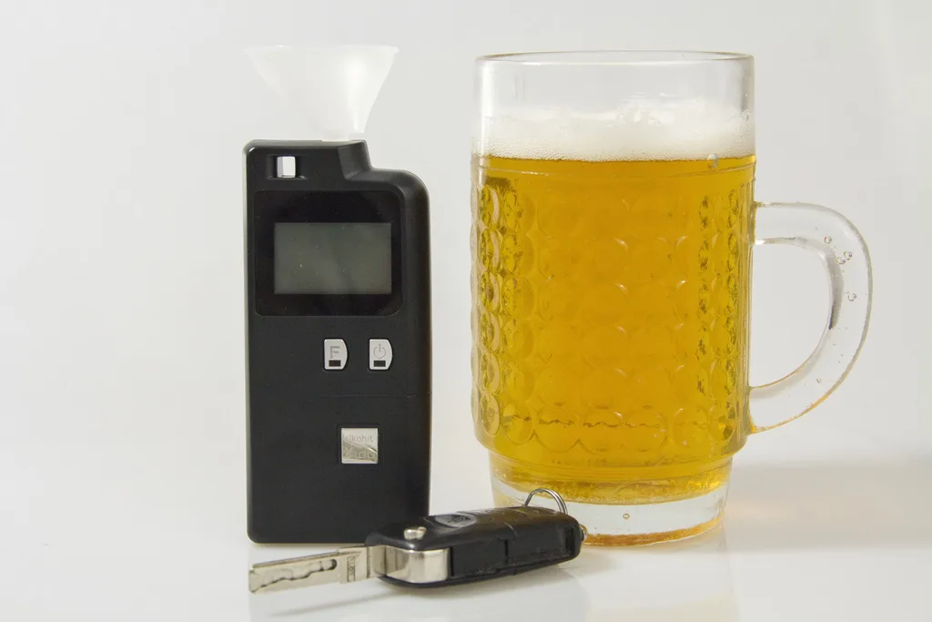 Alcoholímetro junto a una jarra de cerveza y las llaves de un coche