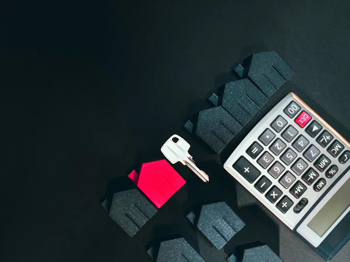 Llave, casa en miniatura y calculadora para calcular el alquiler