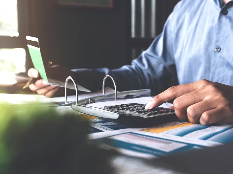 Persona revisando cuentas con una calculadora y una tarjeta bancaria