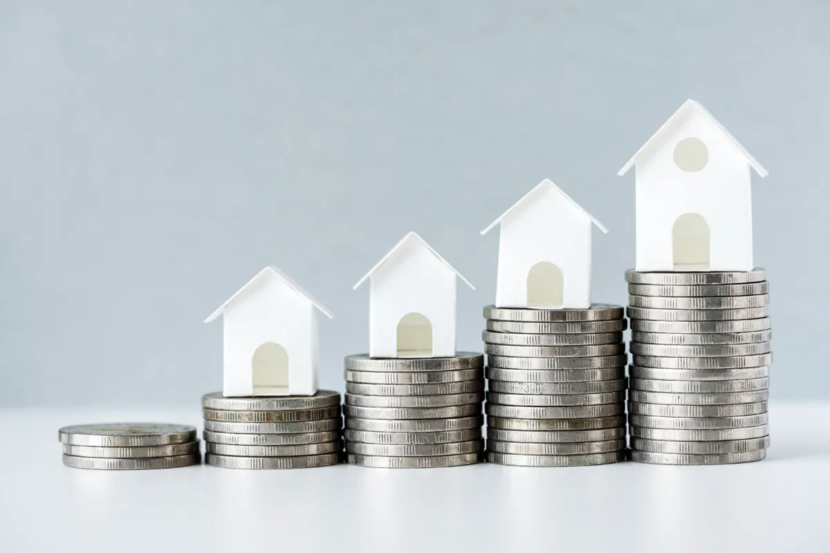 Casas en miniatura sobre pilas de monedas crecientes