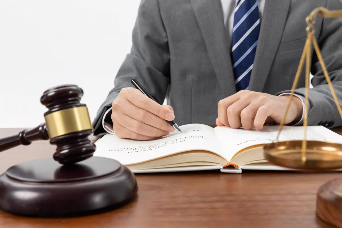 Abogado revisando un código junto a un mazo y una balanza de la justicia