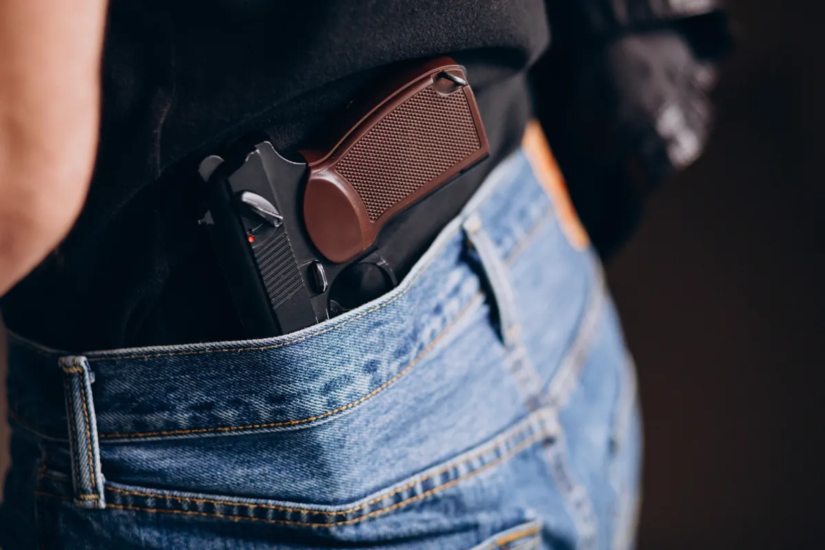 Pistola guardada en la cintura del pantalón de una persona